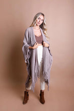 Load image into Gallery viewer, Model wearing the Tahoe open knit fringe ruana with white pants
